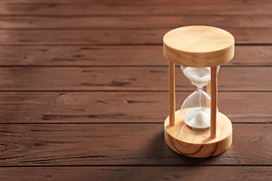 Photo of Hourglass with flowing sand on table. Time management