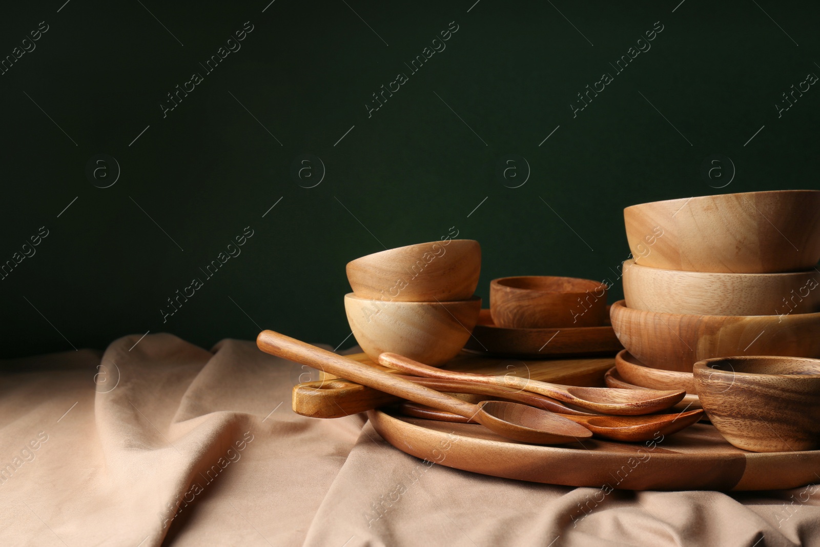 Photo of Set of wooden dishware and utensils on table against green background. Space for text