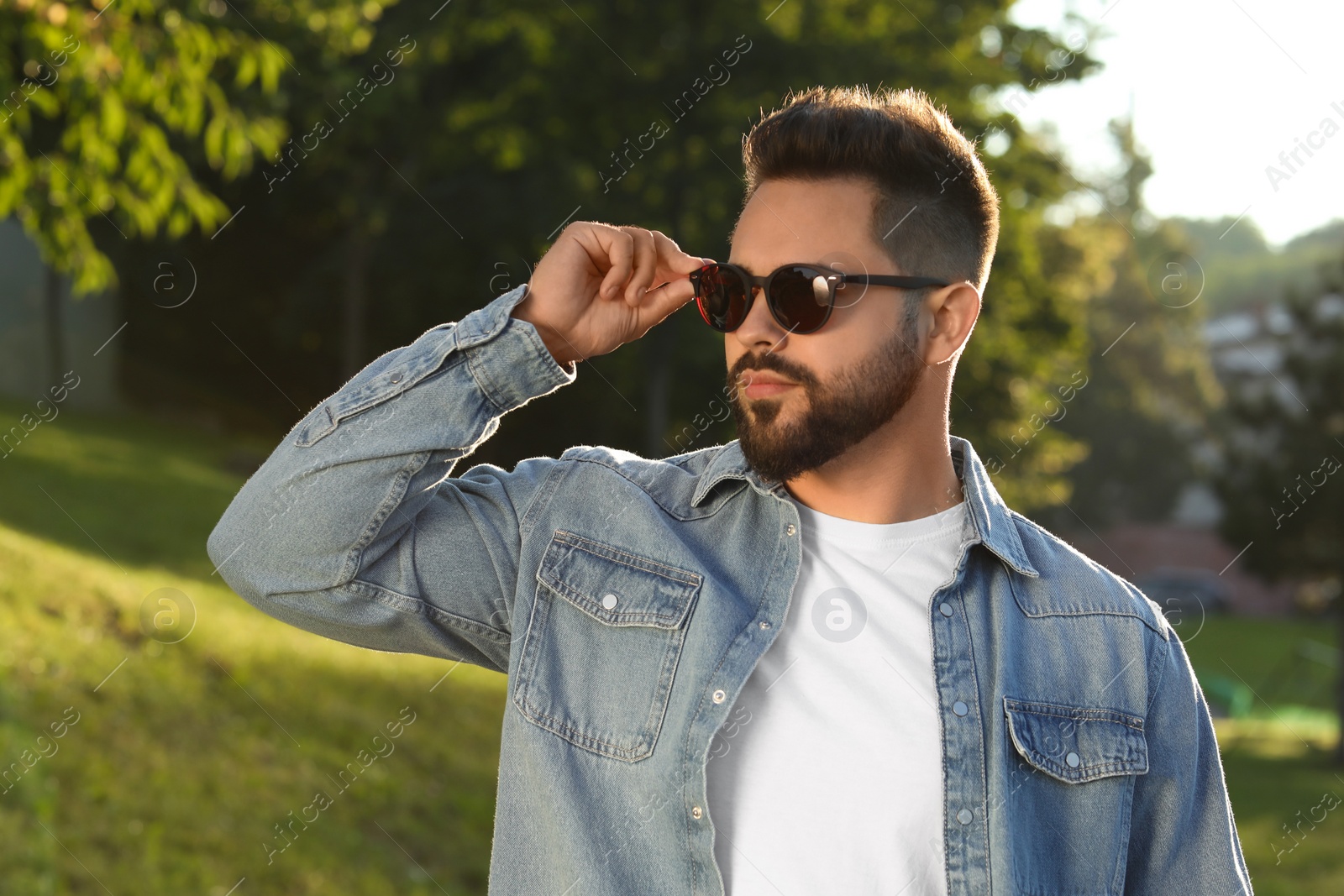 Photo of Handsome young man wearing sunglasses in park