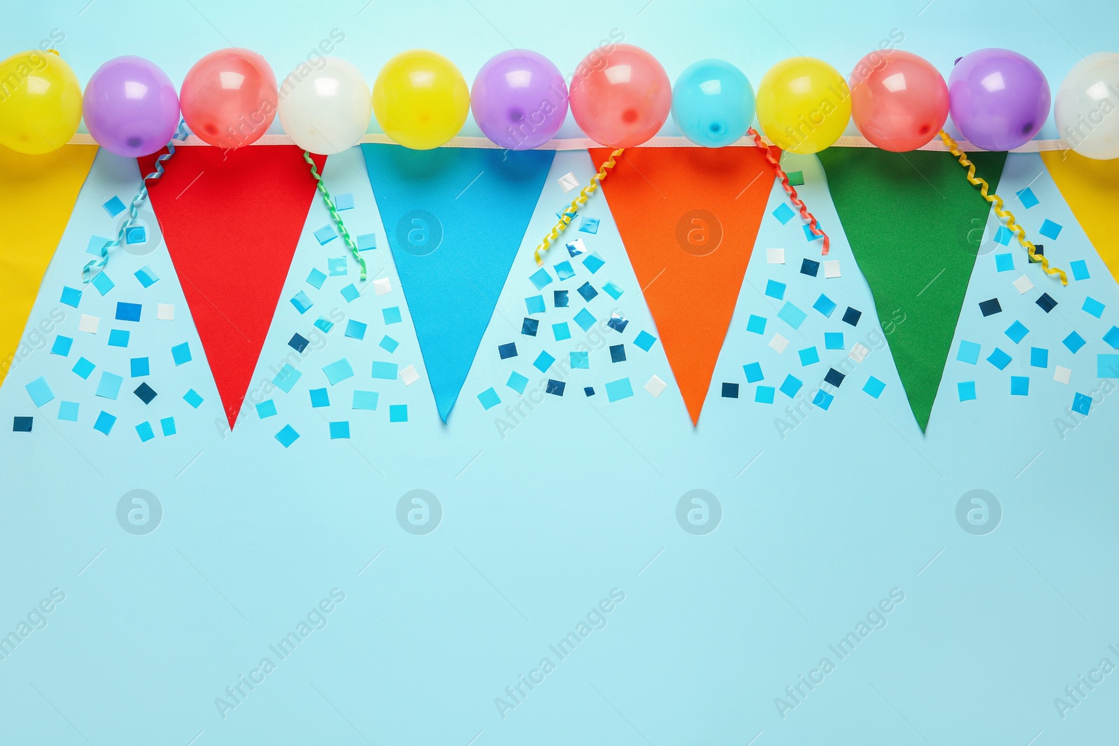 Photo of Bunting with colorful triangular flags and other festive decor on light blue background, flat lay. Space for text