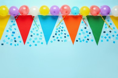 Bunting with colorful triangular flags and other festive decor on light blue background, flat lay. Space for text