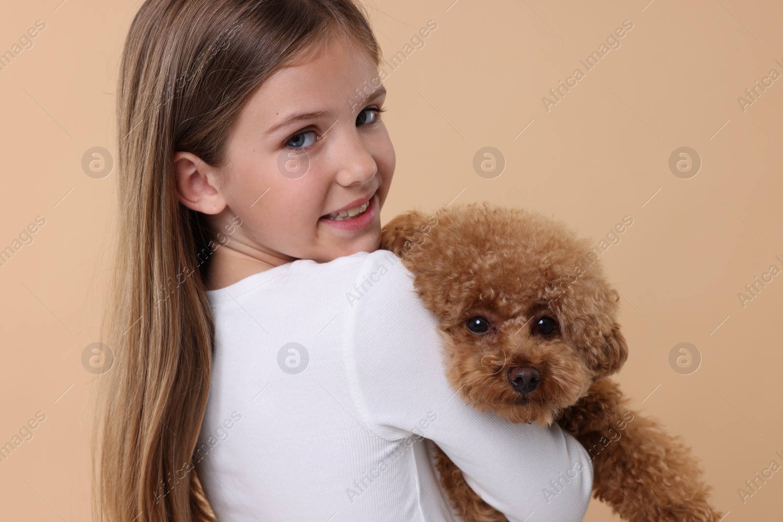 Photo of Little child with cute puppy on beige background. Lovely pet