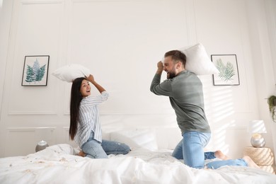 Photo of Happy young couple having fun pillow fight in bedroom