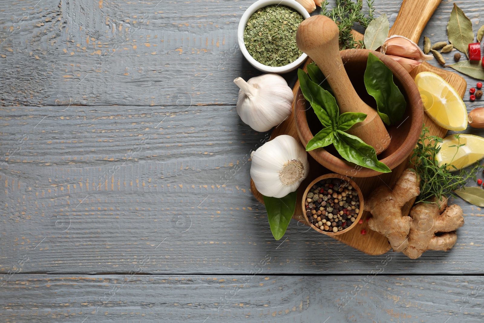 Photo of Different natural spices and herbs on grey wooden table, flat lay. Space for text