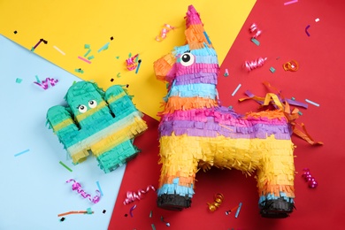 Photo of Festive pinatas, streamers and glitter on color background, flat lay