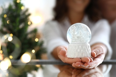 Happy couple celebrating Christmas, focus on hands with snow globe