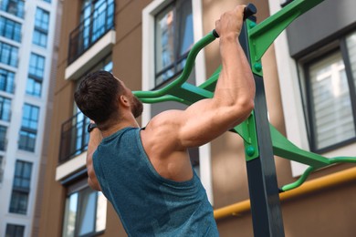 Photo of Man doing pull ups at outdoor gym, low angle view