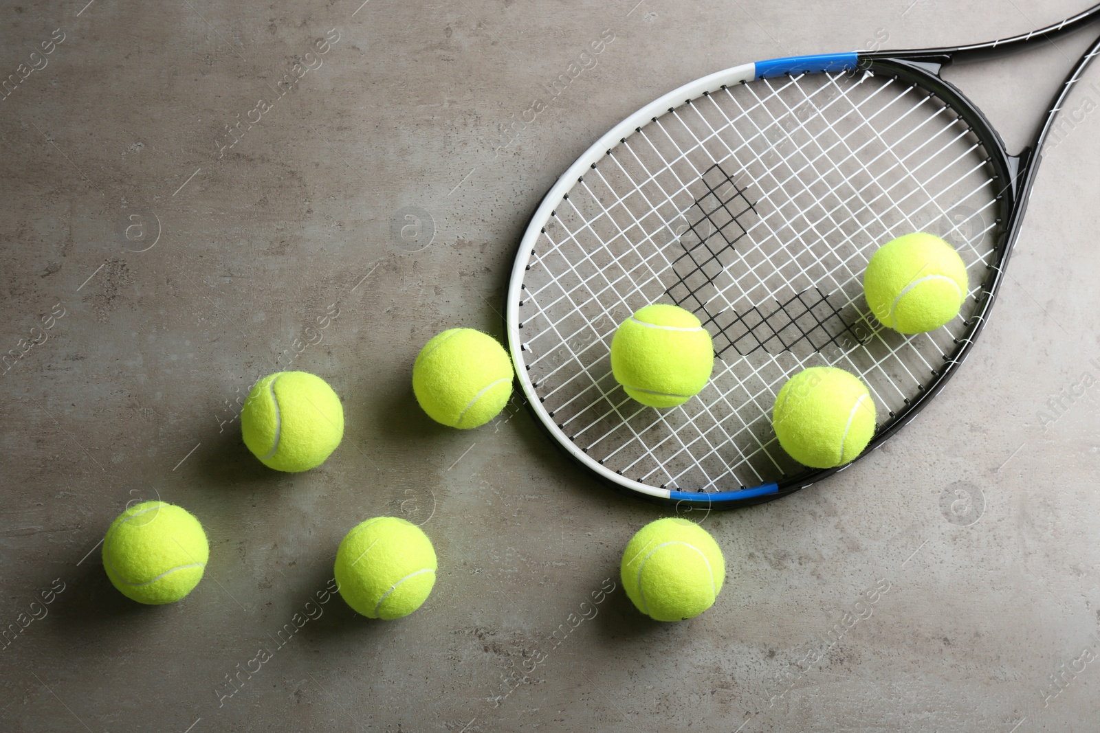 Photo of Tennis racket and balls on grey table, flat lay. Sports equipment