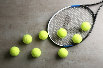 Tennis racket and balls on grey table, flat lay. Sports equipment