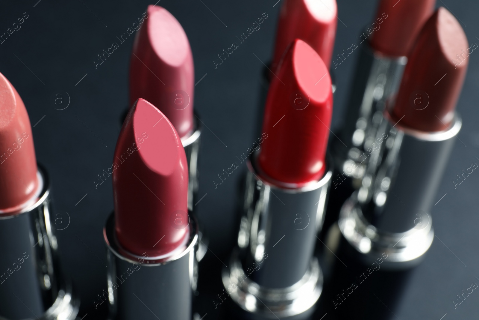 Photo of Set of different lipsticks on grey background, closeup. Cosmetic product