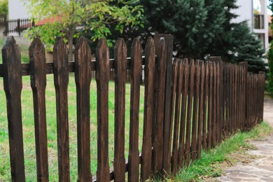 Photo of Low wooden fence near trees and green grass outdoors