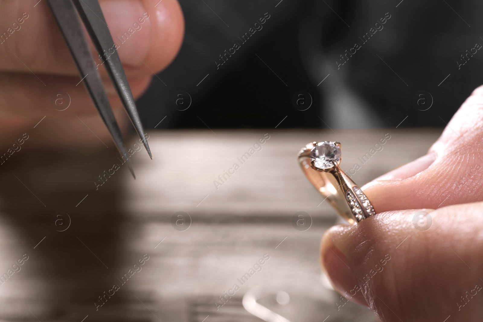 Photo of Male jeweler examining diamond ring in workshop, closeup view