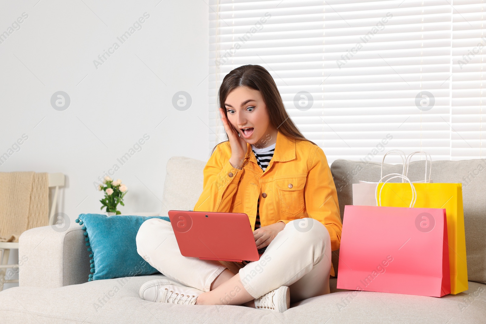 Photo of Special Promotion. Emotional woman looking at laptop on sofa indoors