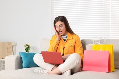 Special Promotion. Emotional woman looking at laptop on sofa indoors