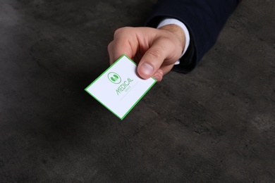 Photo of Man holding medical business card on dark background, closeup. Nephrology service