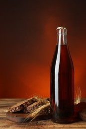 Photo of Bottle of delicious fresh kvass, spikelets and bread on wooden table. Space for text