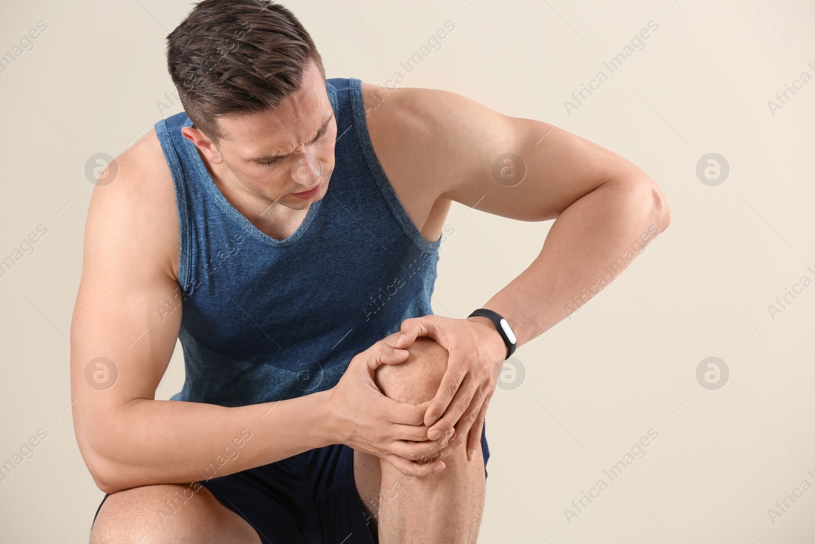 Photo of Man in sportswear suffering from knee pain on light background