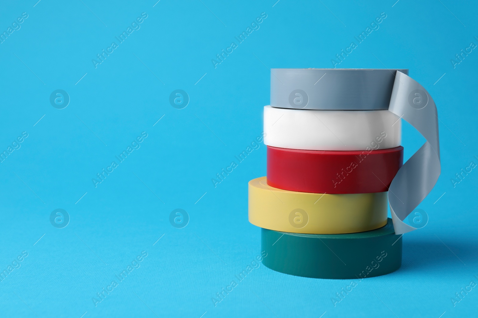 Photo of Colorful insulating tapes on light blue background. Space for text