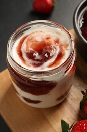 Tasty yoghurt with jam and strawberries on black table, closeup