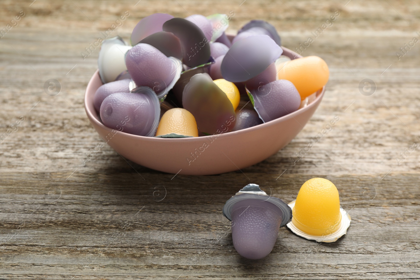 Photo of Bowl with tasty bright jelly cups on wooden table