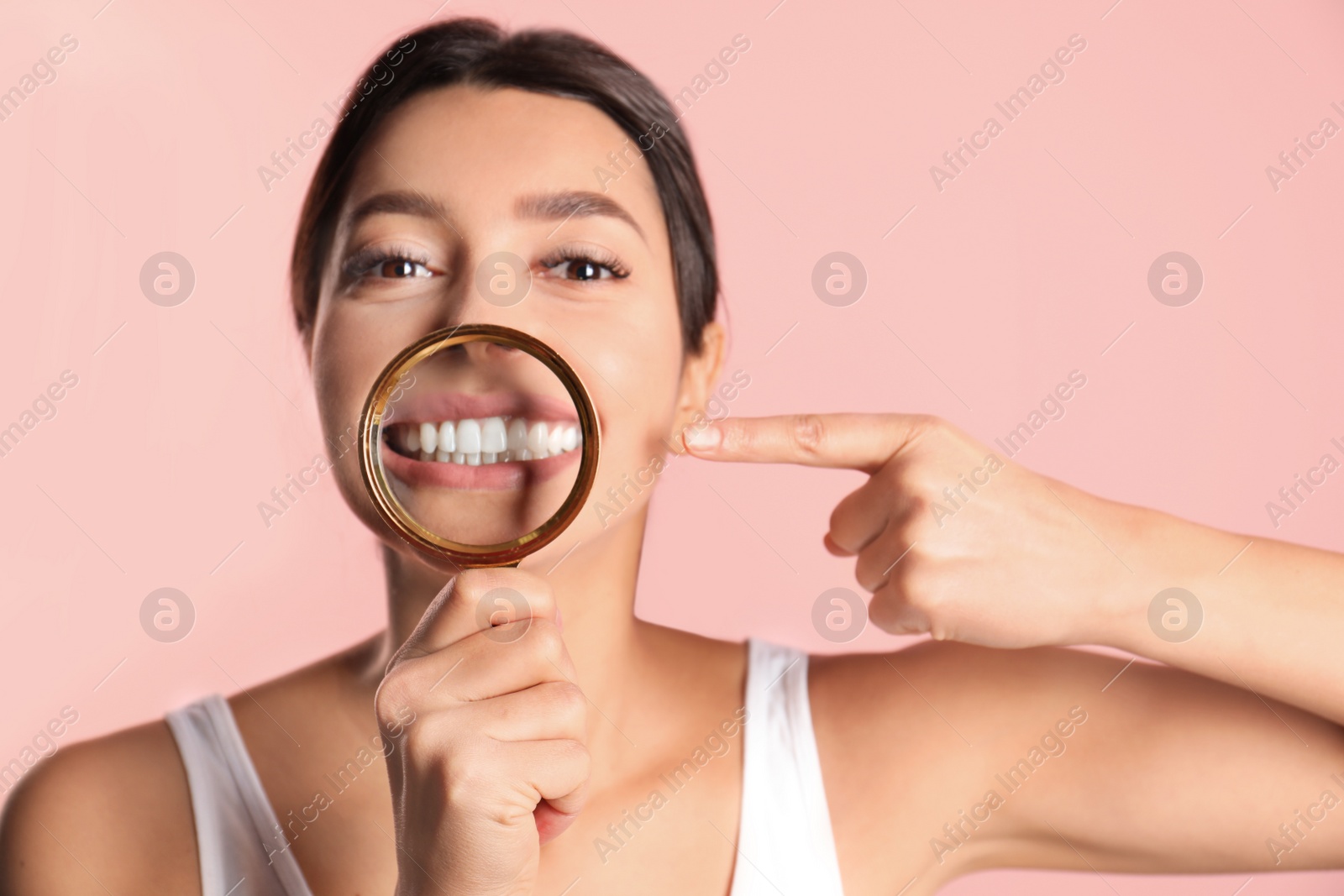 Photo of Young woman with healthy teeth and magnifier on color background