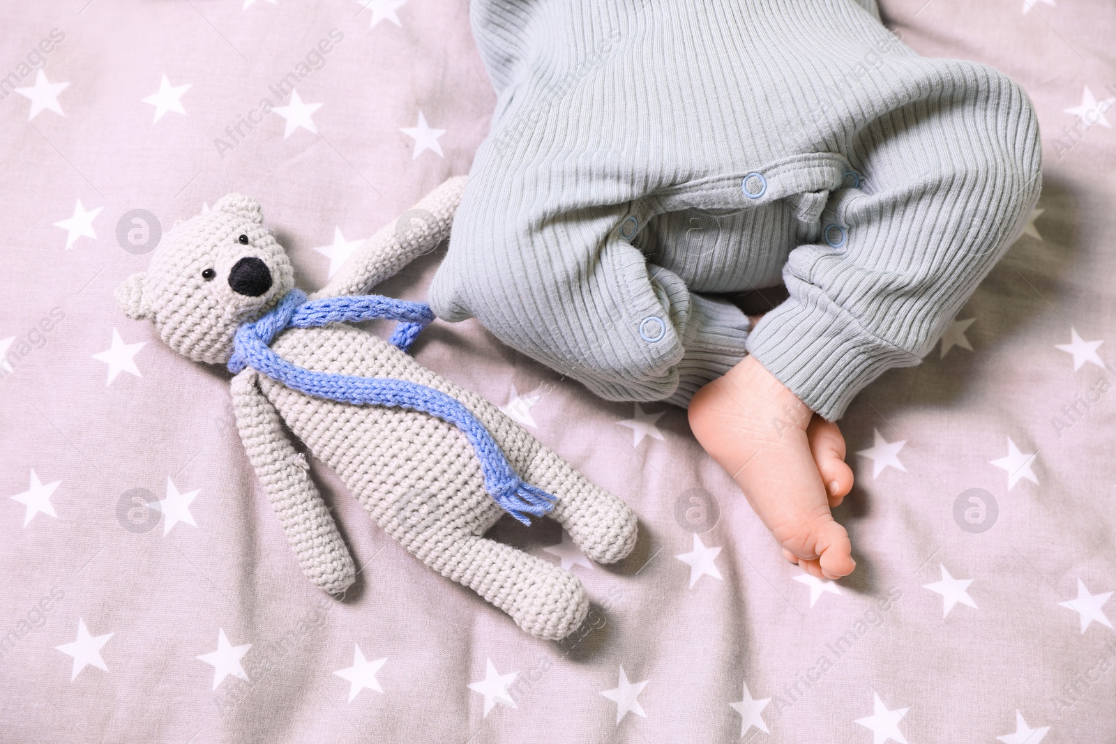 Photo of Cute newborn baby with toy bear on bed, top view