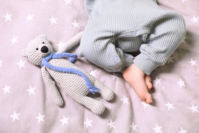 Cute newborn baby with toy bear on bed, top view