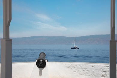 Iron cannon near sea with sailboat on sunny day