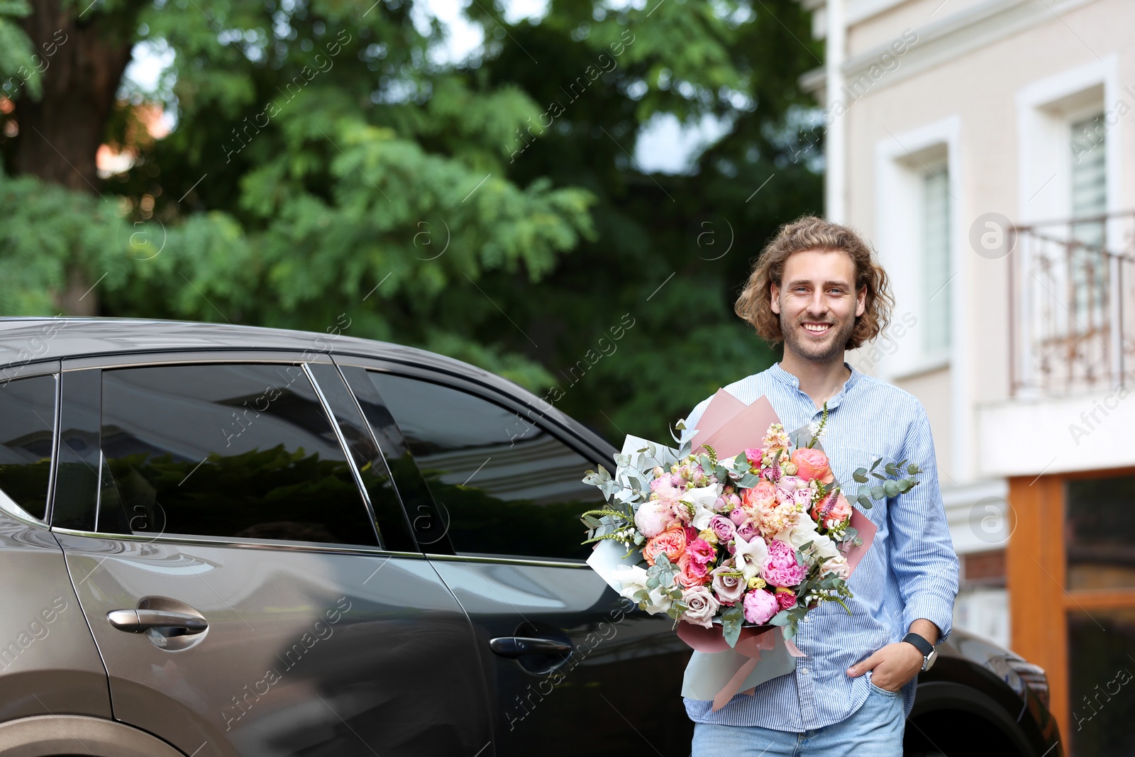 Photo of Young handsome man with beautiful flower bouquet near car on street