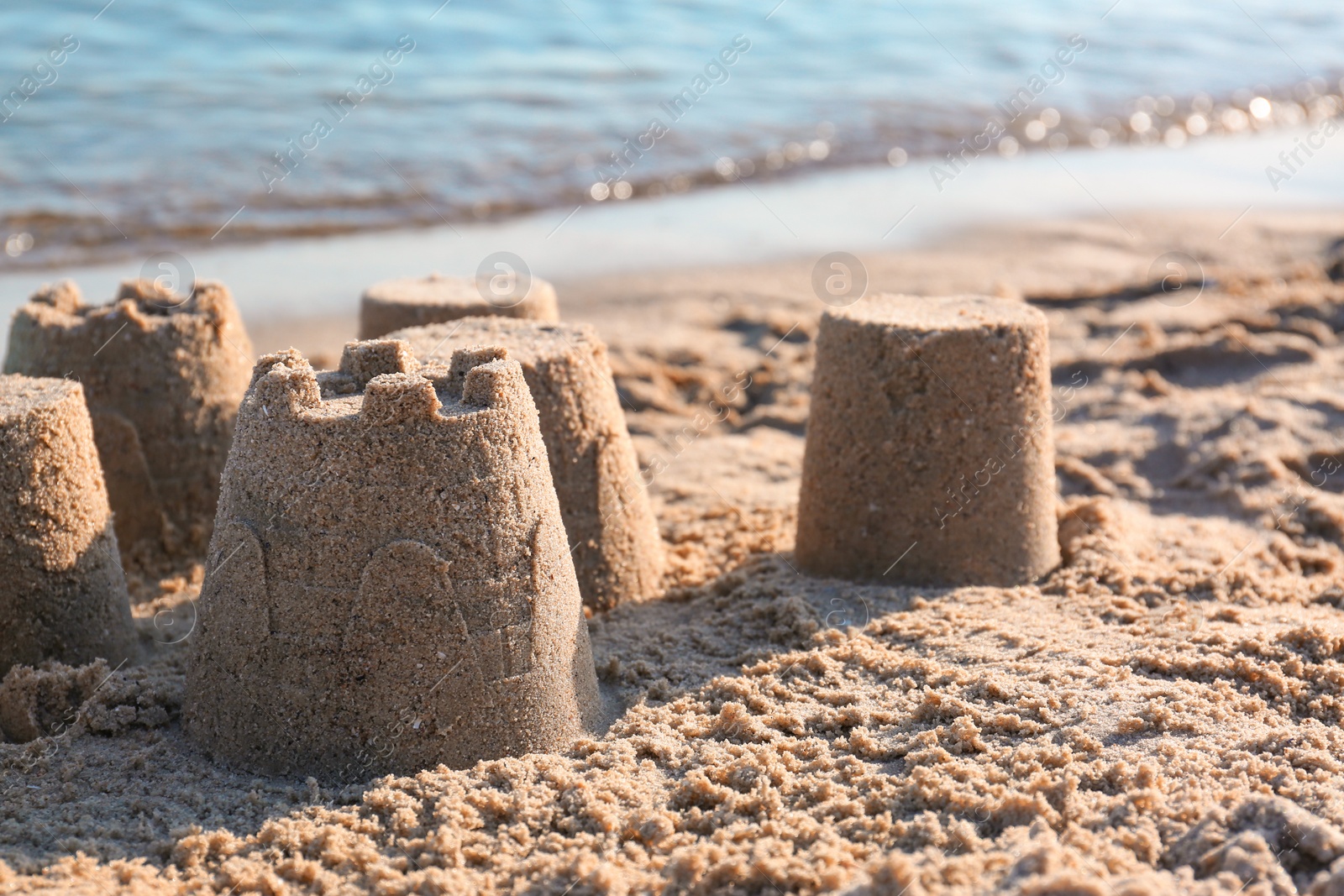 Photo of View of beach with little sand figures near sea on sunny summer day. Space for text