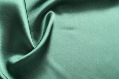 Photo of Crumpled green silk fabric as background, top view. Space for text