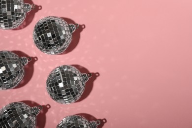 Photo of Bright shiny disco balls on pink background, flat lay. Space for text