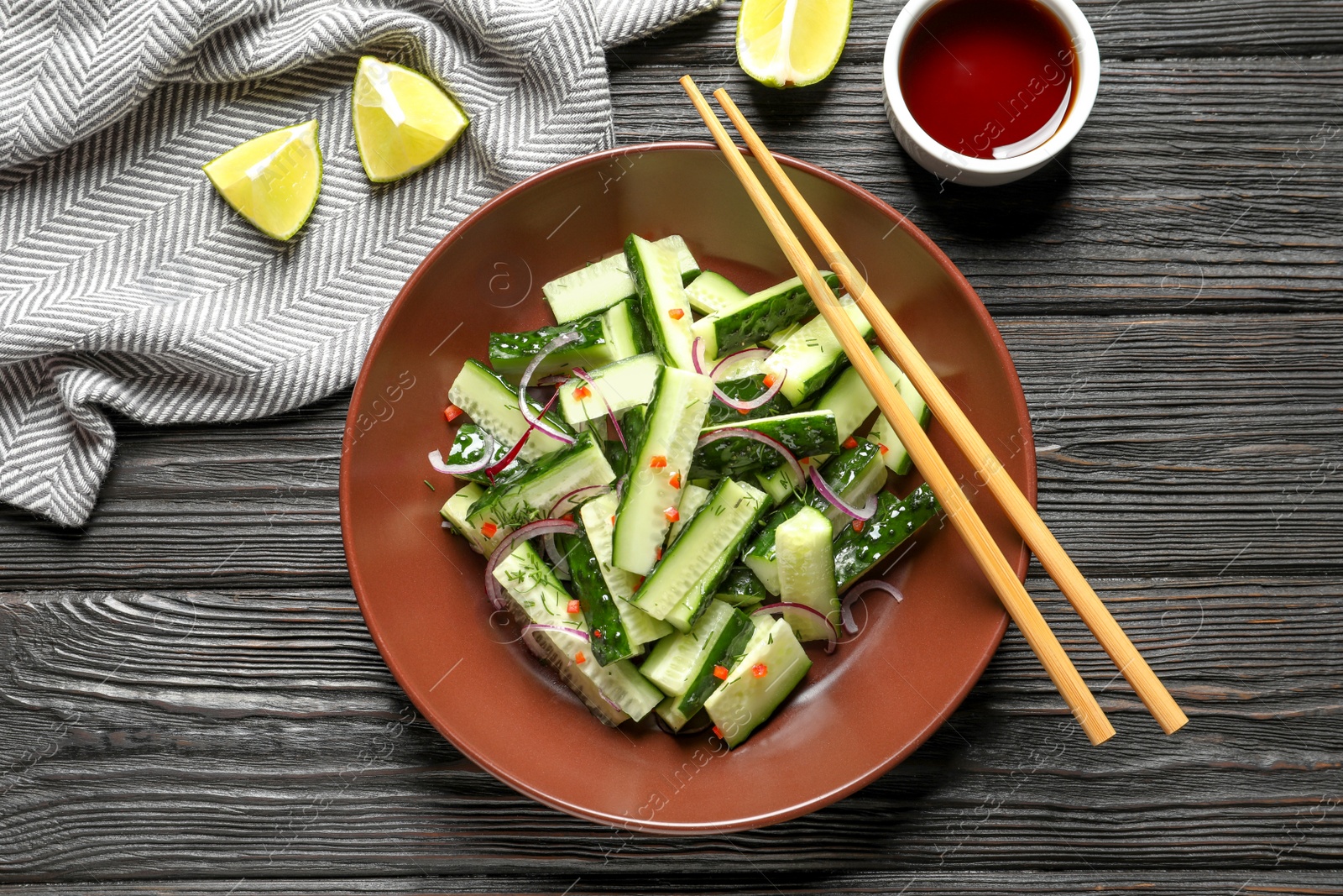 Photo of Plate with delicious cucumber salad served on wooden table, top view