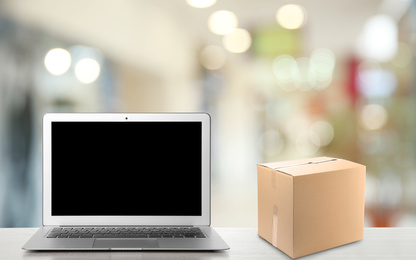 Image of Online selling. Laptop and parcel on table in store