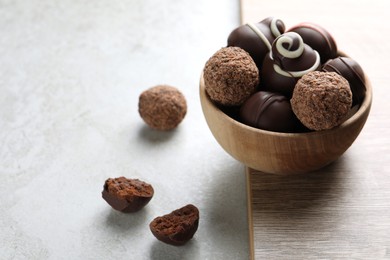 Many different delicious chocolate truffles on light table, space for text