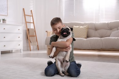 Boy hugging his cute pug in living room