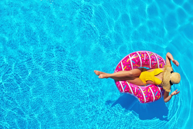 Young woman with inflatable ring in swimming pool, top view. Space for text