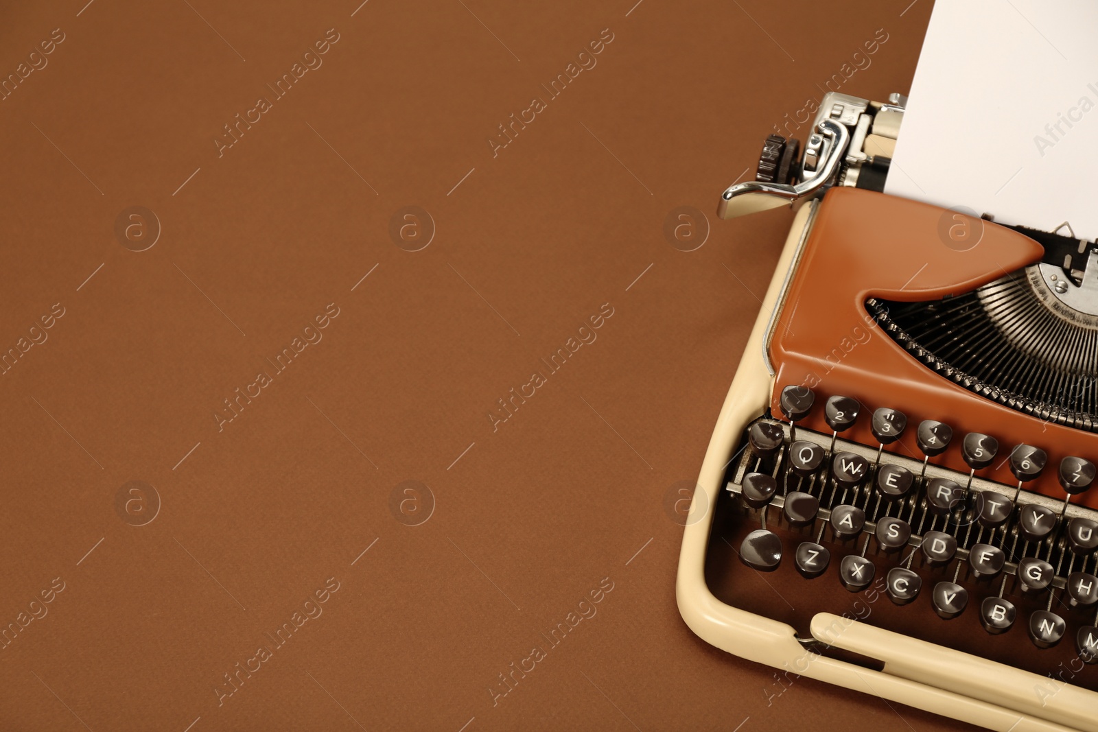 Photo of Vintage typewriter on brown background. Space for text