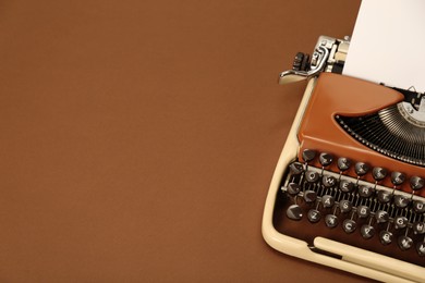 Photo of Vintage typewriter on brown background. Space for text