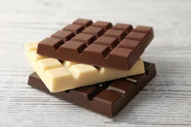 Different yummy chocolate bars on wooden background