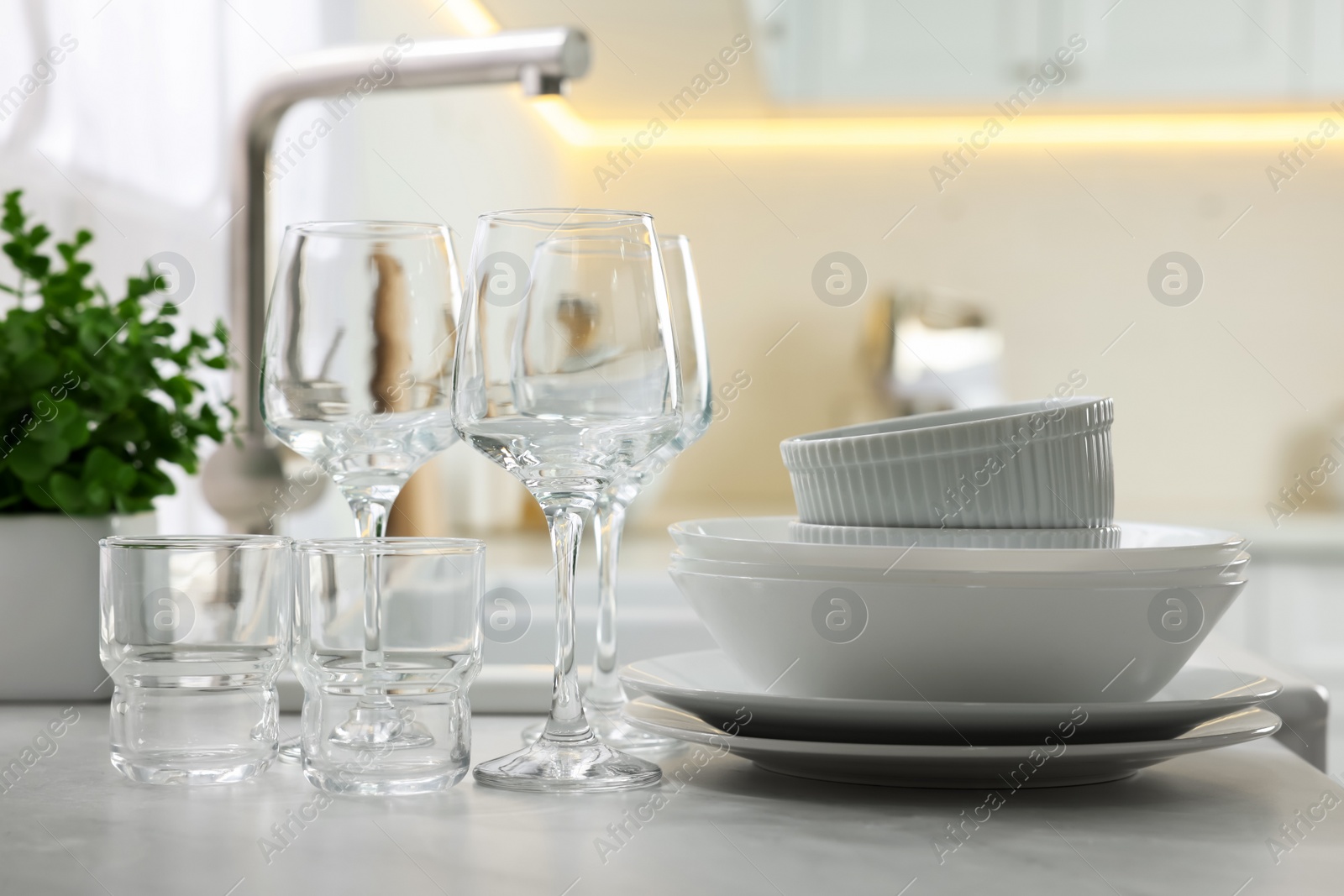 Photo of Different clean dishware and glasses on countertop in kitchen