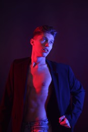 Sexy young man on dark background in neon lights