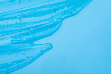 Photo of Pure transparent cosmetic gel on light blue background, closeup