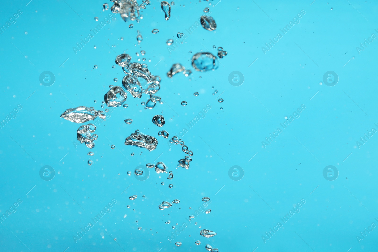 Photo of Air bubbles in water on light blue background