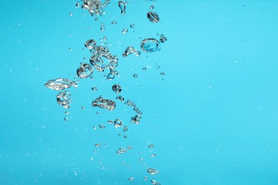 Photo of Air bubbles in water on light blue background