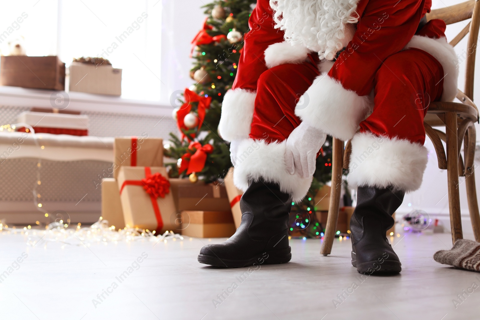 Photo of Authentic Santa Claus putting on traditional costume indoors