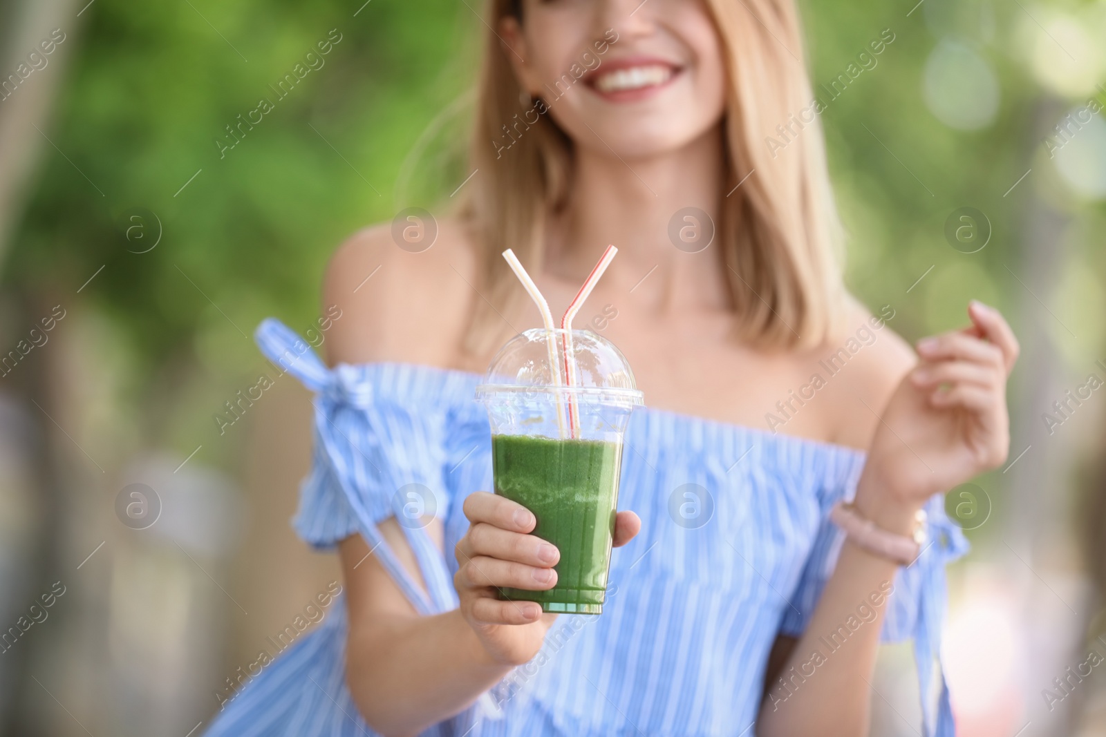 Photo of Young woman with plastic cup of healthy smoothie outdoors