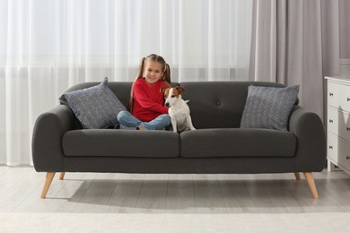 Photo of Cute girl with her dog on sofa at home. Adorable pet