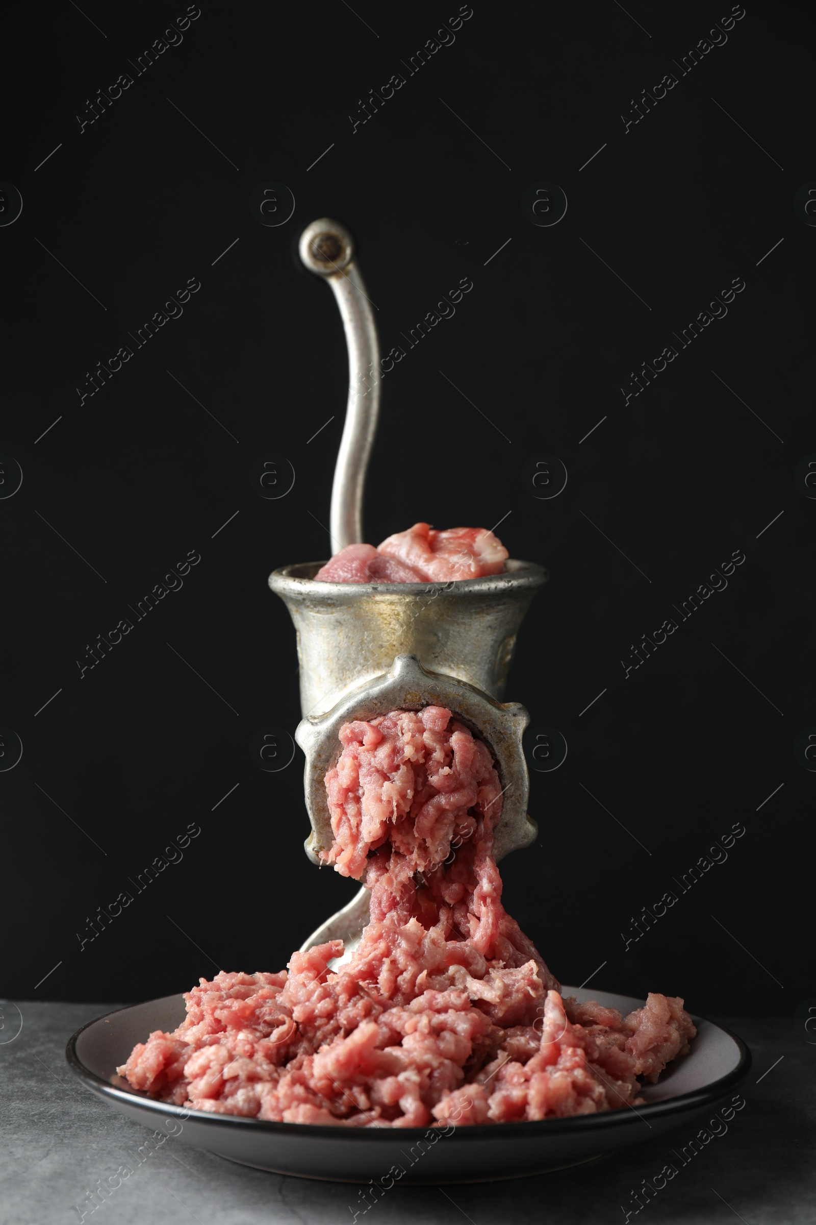 Photo of Manual meat grinder with beef mince on grey table