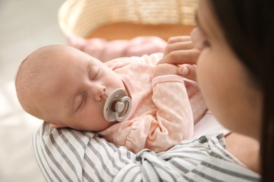 Mother holding her sleeping baby indoors, closeup